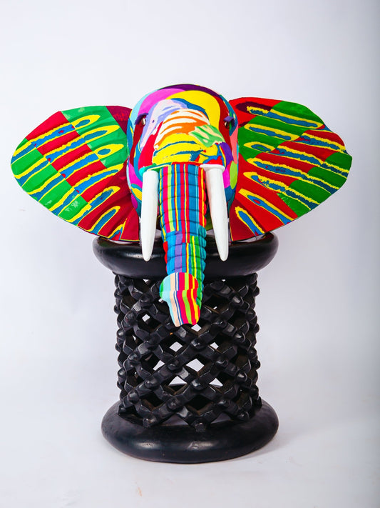 Colourful elephant figurine on a black wooden base against a white background