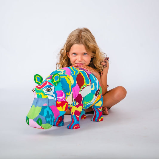 Child with a colourful hippo sculpture on a white background