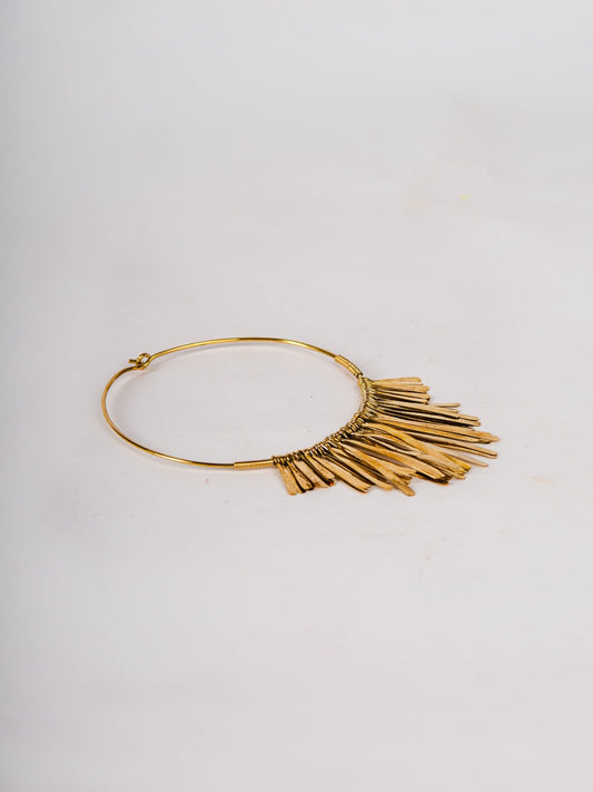 Gold fringe necklace on a light gray background