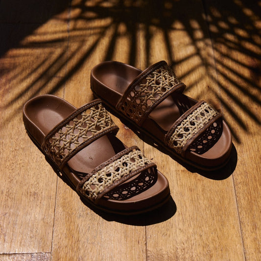 Brown sandals with woven straps on a wooden surface