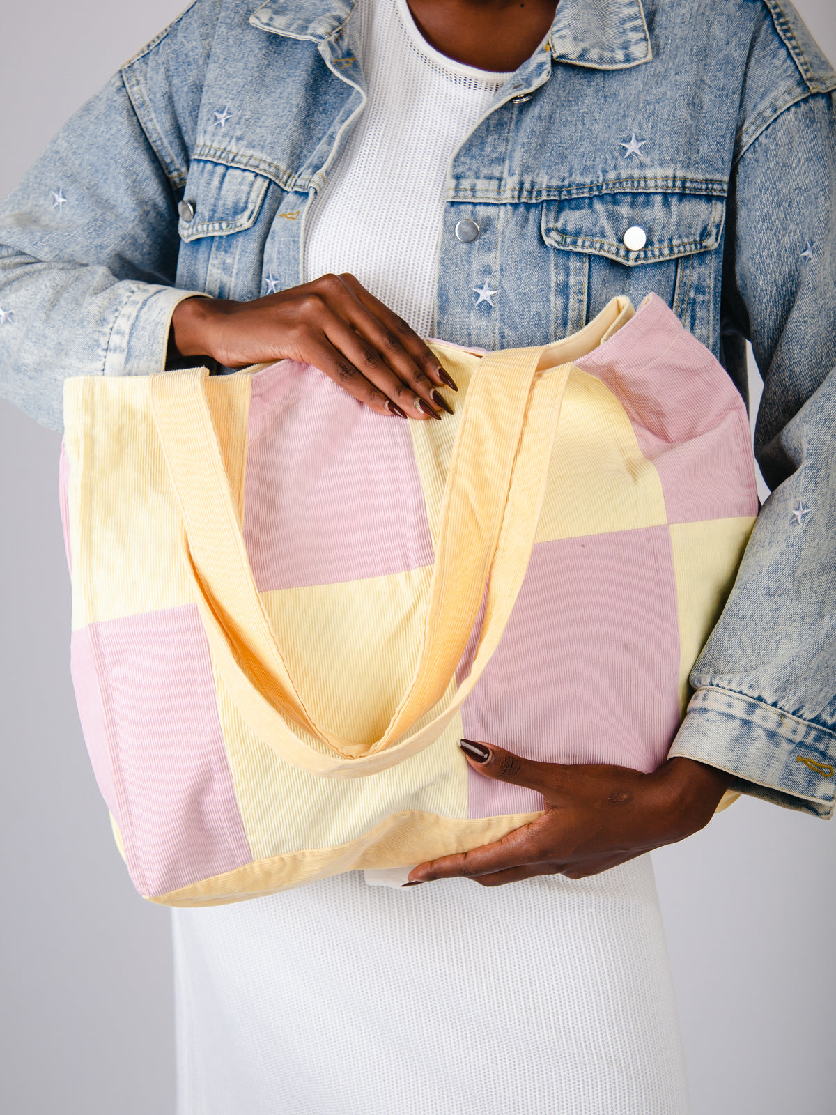 Person holding a pastel checkered bag against a neutral background
