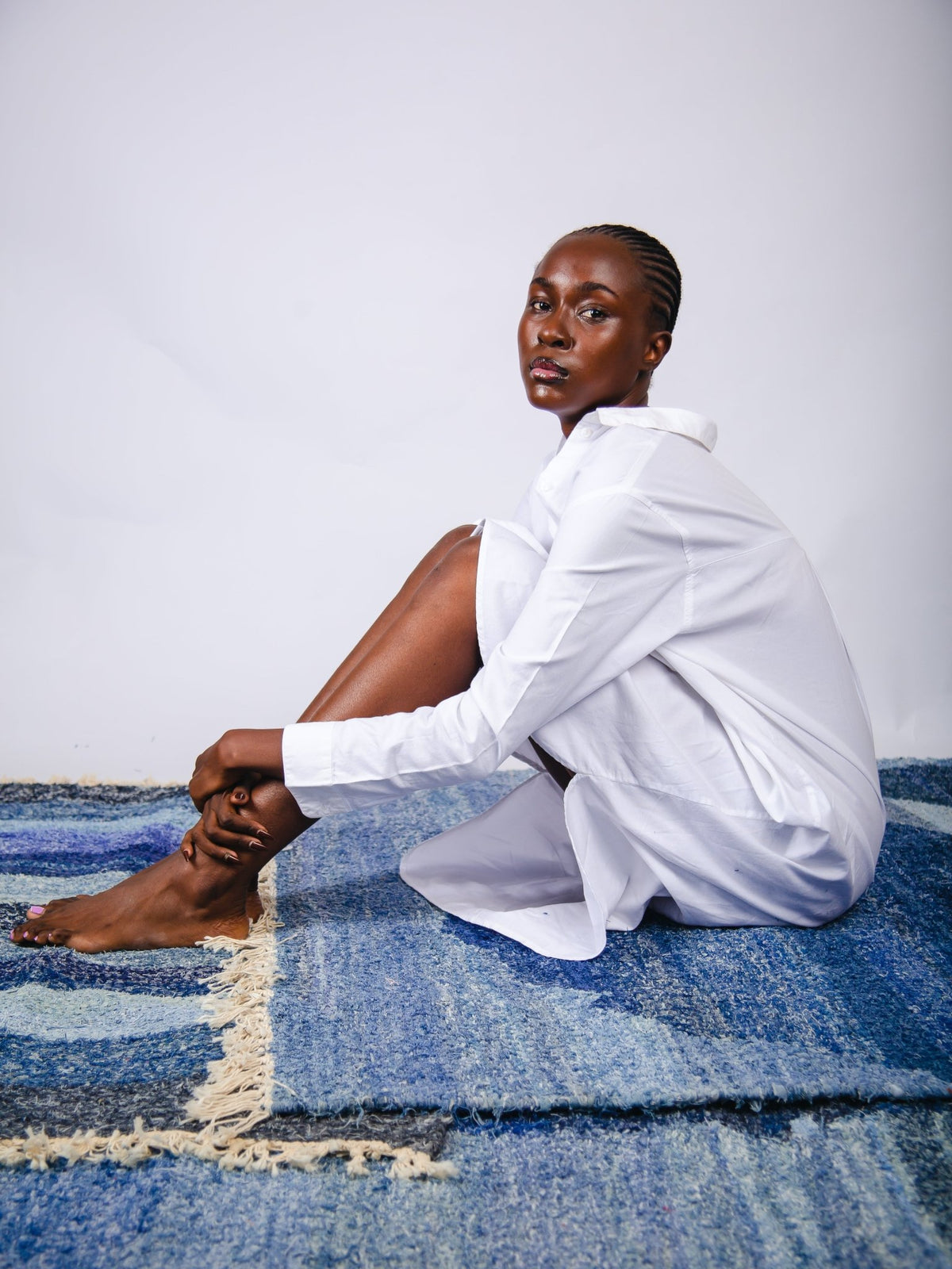 Person wearing a white shirt sitting on a blue textured surface with a plain background