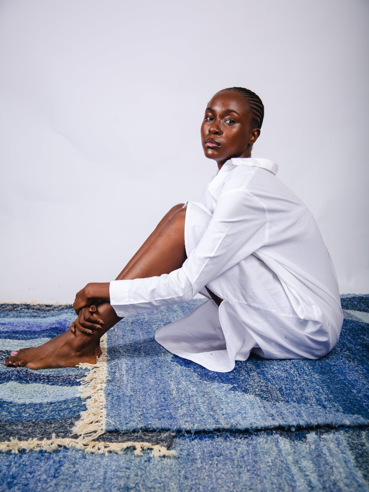 Person wearing a white shirt sitting on a blue textured surface with a plain background