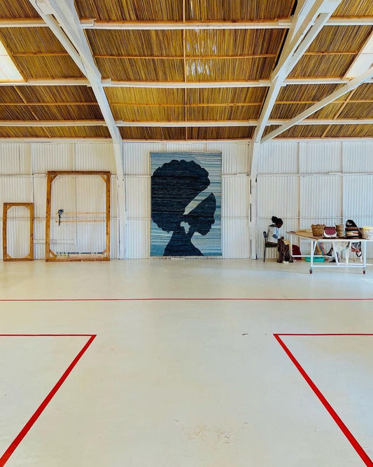 Large mural of a woman's silhouette on a wall in a spacious indoor setting with wooden ceiling.