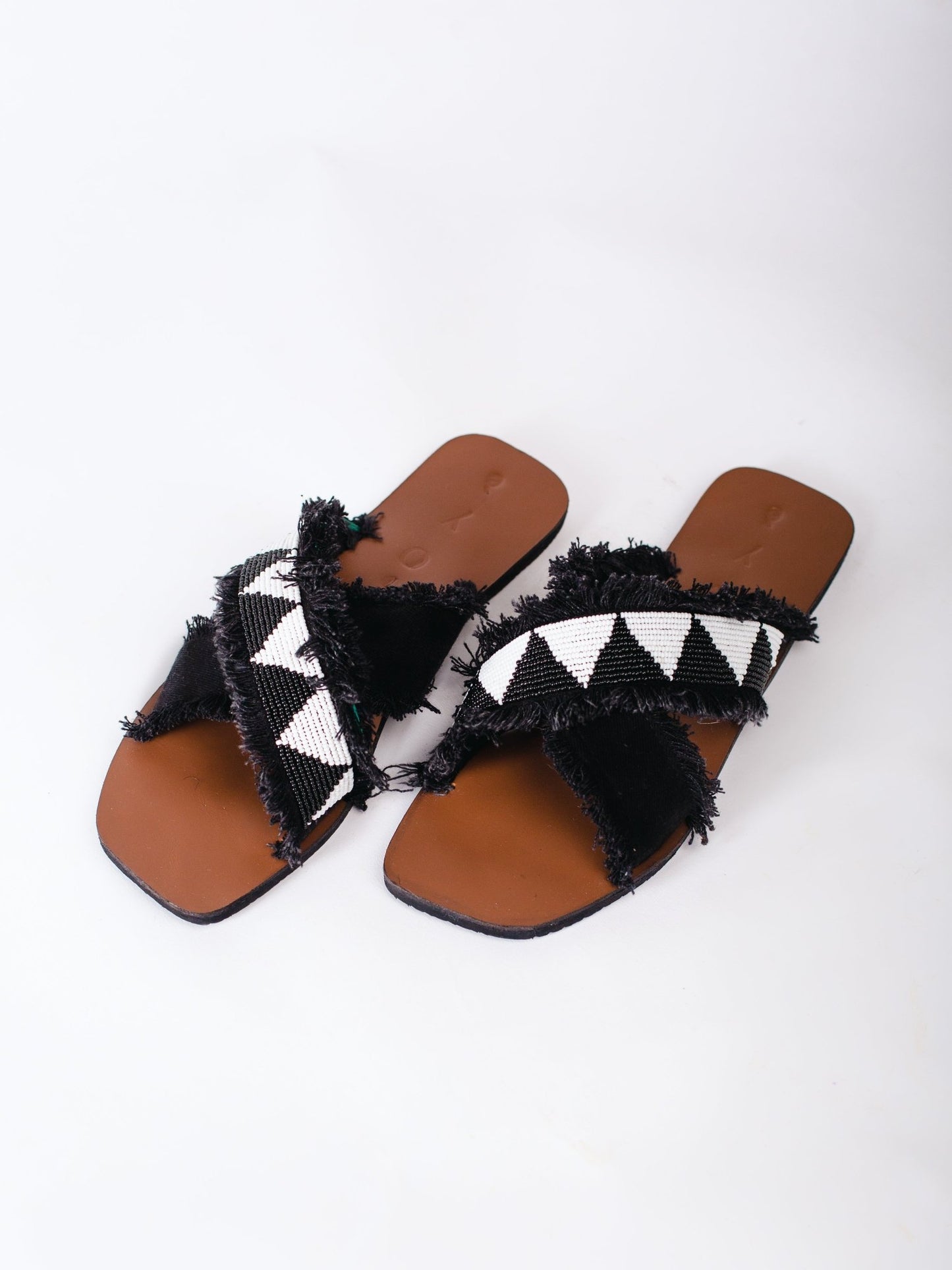 Pair of black and white sandals with brown soles on a white background