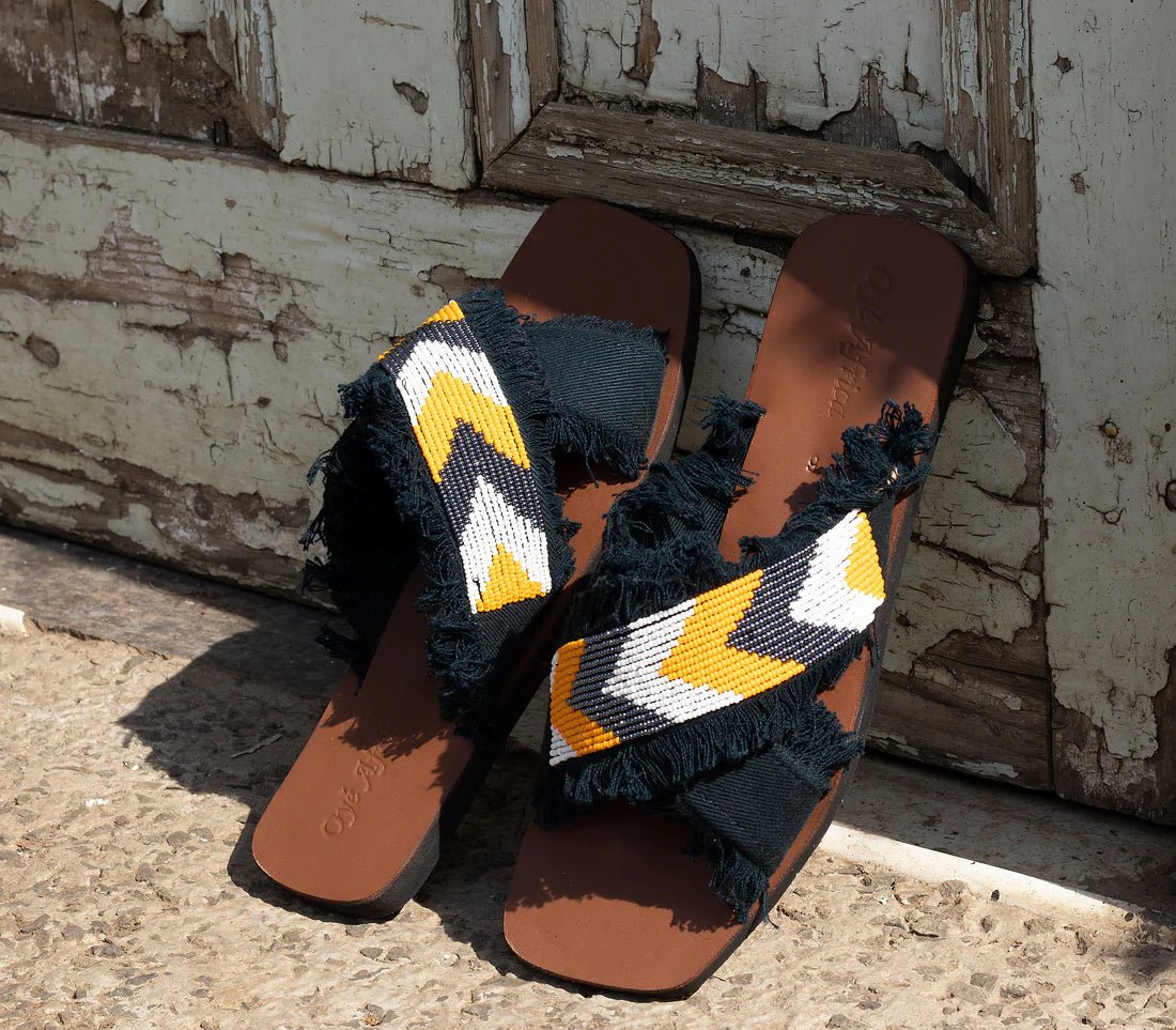 Brown sandals with decorative straps against a rustic wooden background