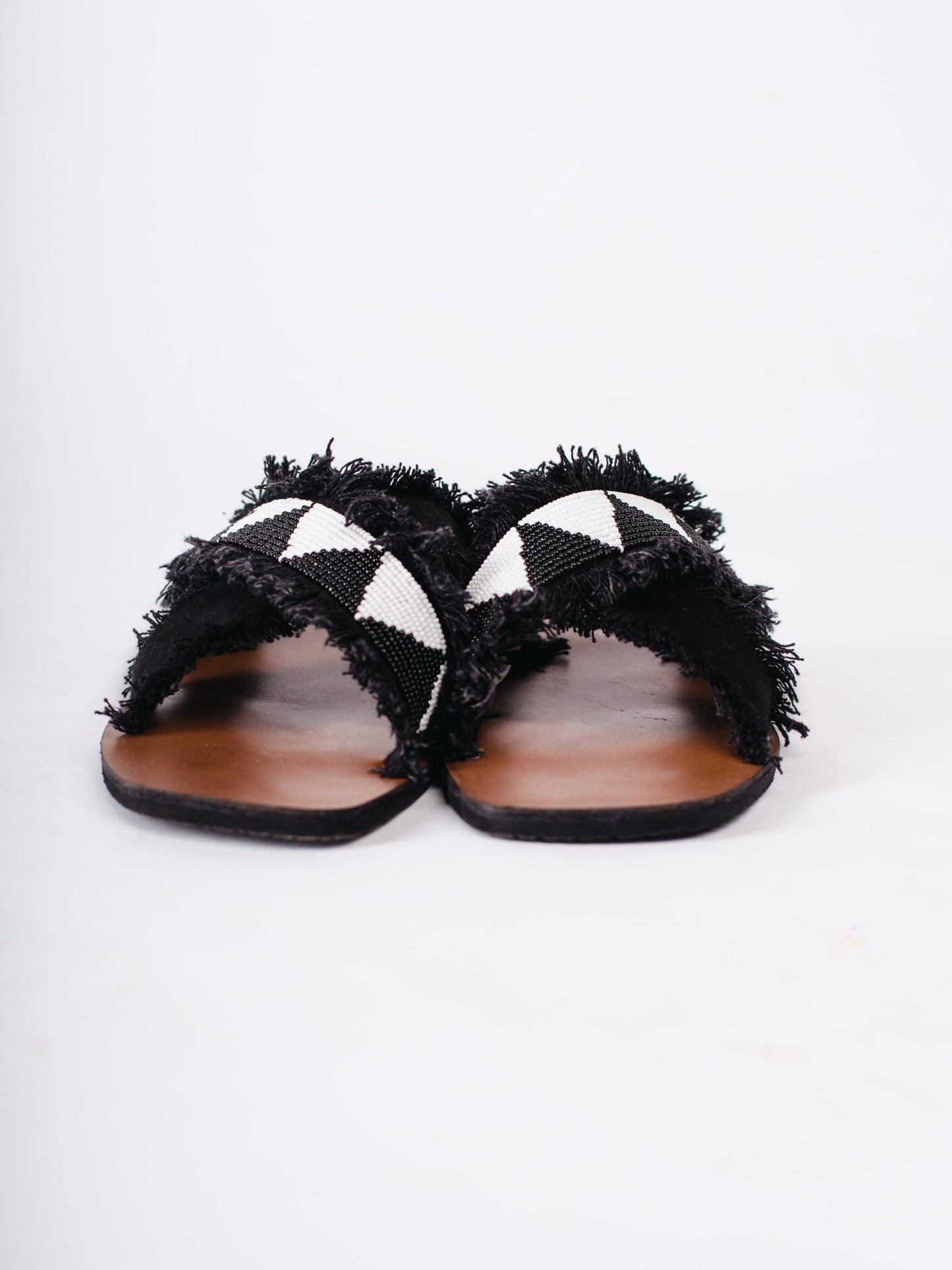 Pair of black and white sandals with frayed edges on a white background