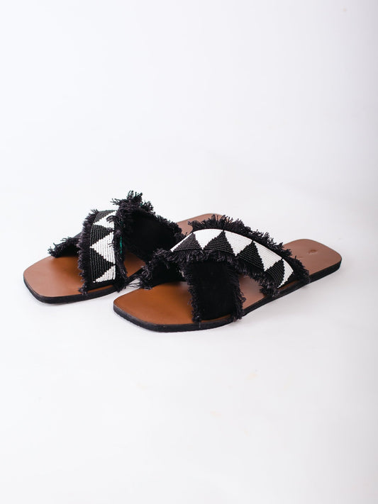Black and white patterned sandals with brown soles on a white background