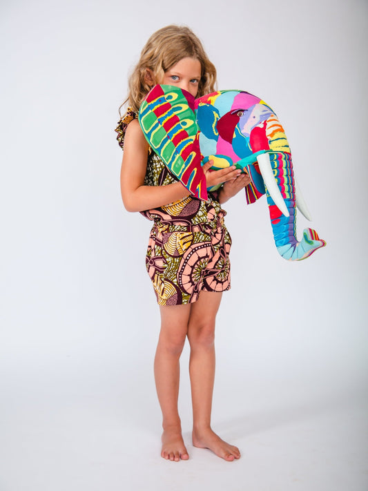 Child holding a colourful elephant-shaped sculpture against a white background