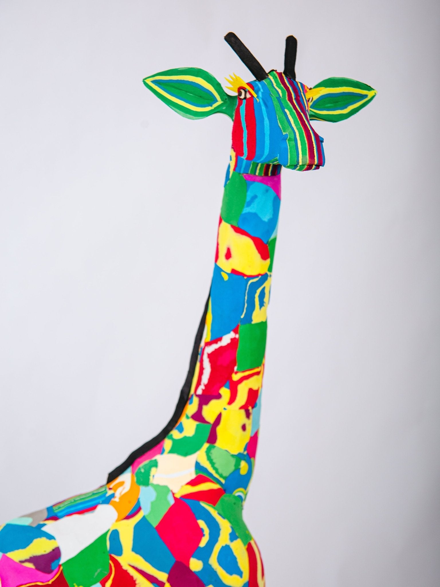 Colourful stuffed giraffe sculpture on a white background