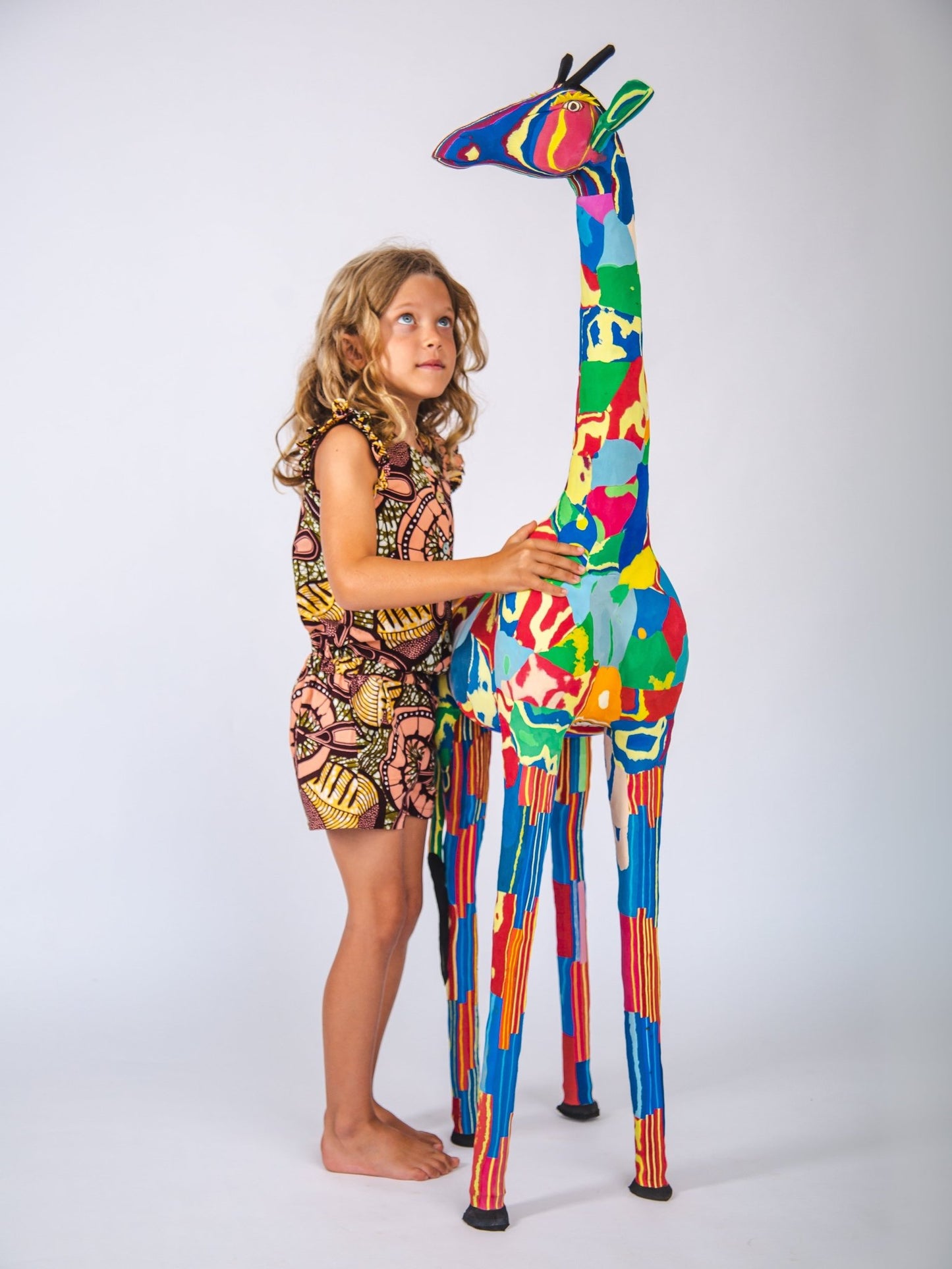 Child holding a colourful giraffe sculpture against a white background
