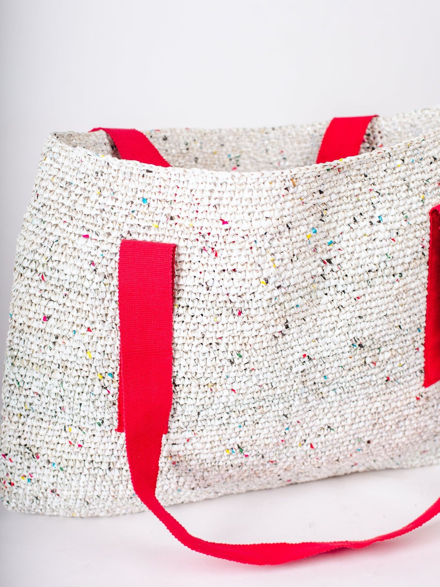 Textured tote bag with red handles on a white background