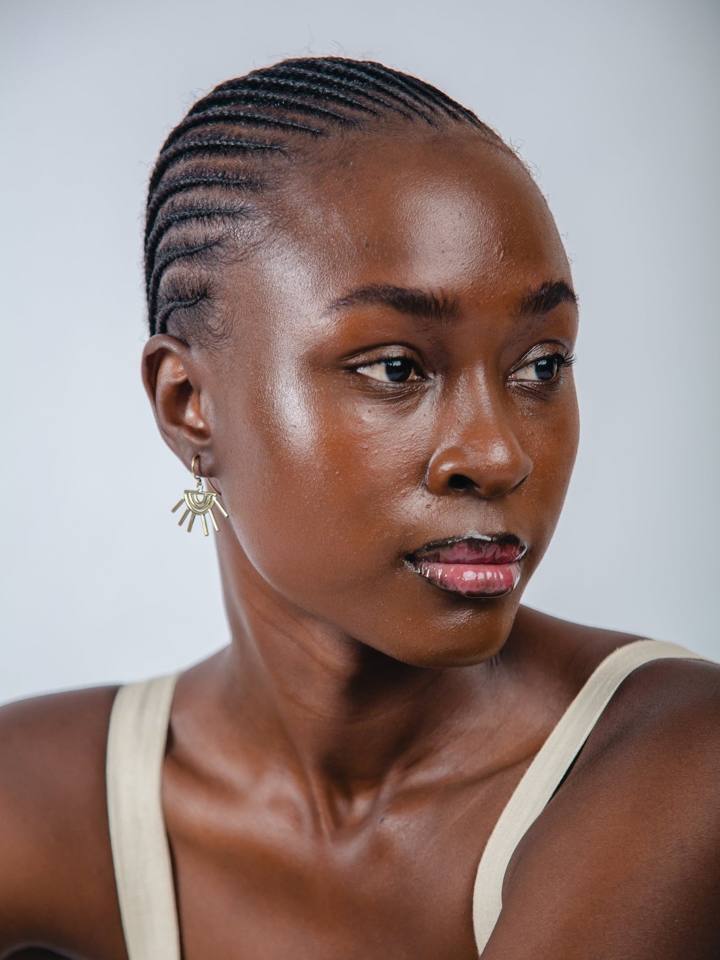 Woman with braided hair wearing a beige top against a plain background