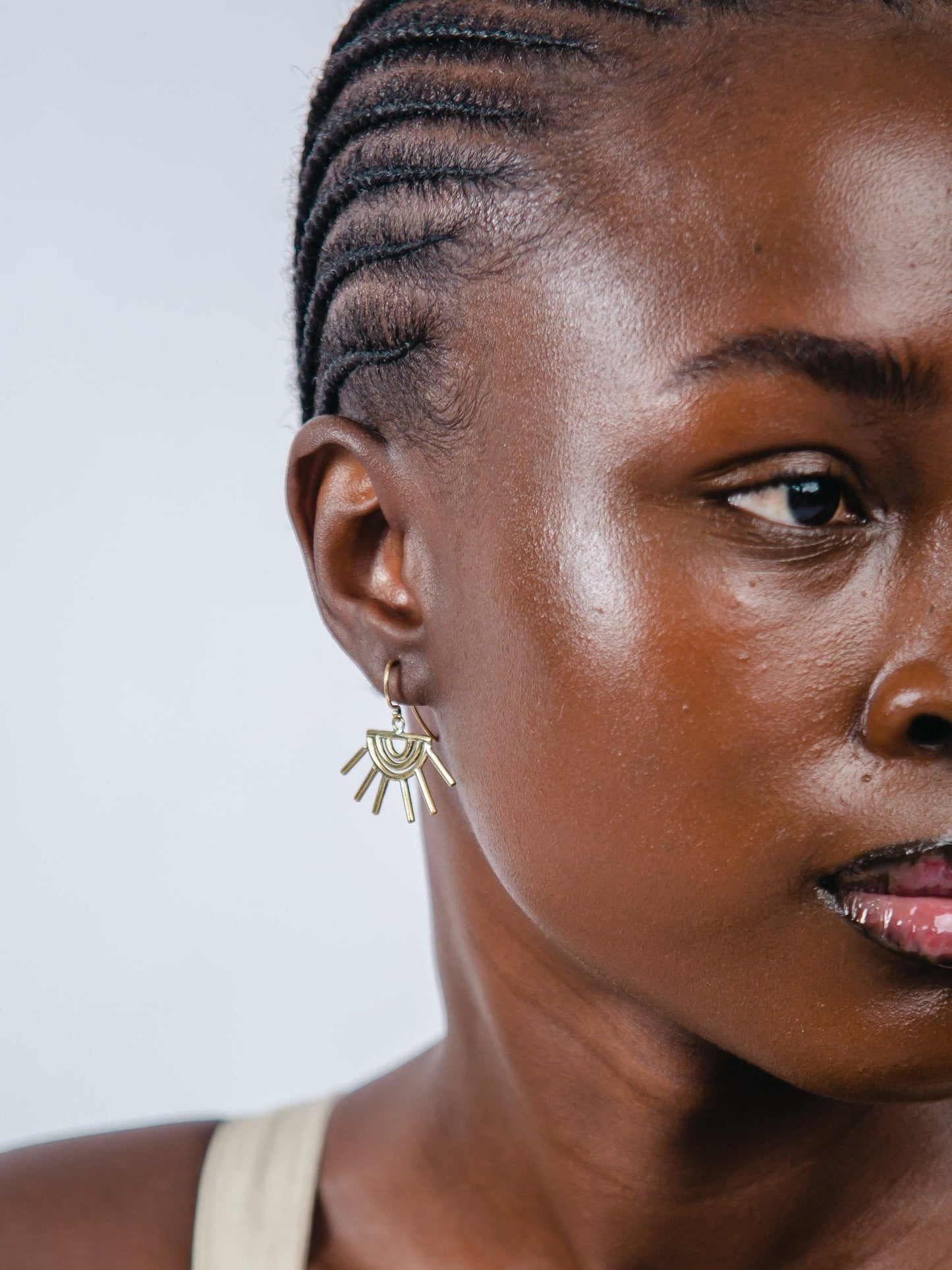 Close-up of a woman wearing gold earrings with a plain background