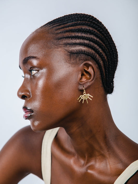Woman with styled hair and gold earrings against a light background