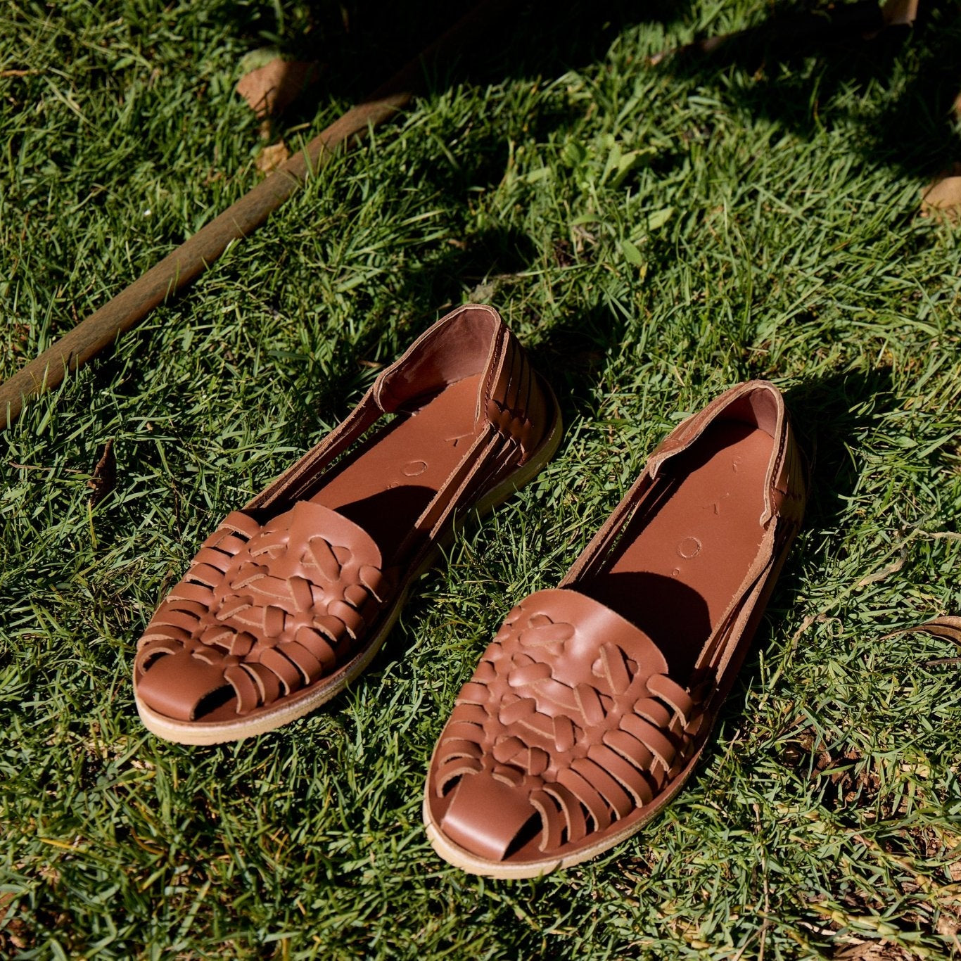 Brown sandals with woven design on a grassy surface