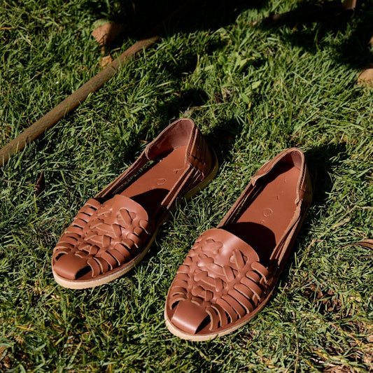 Brown sandals with woven design on a grassy surface