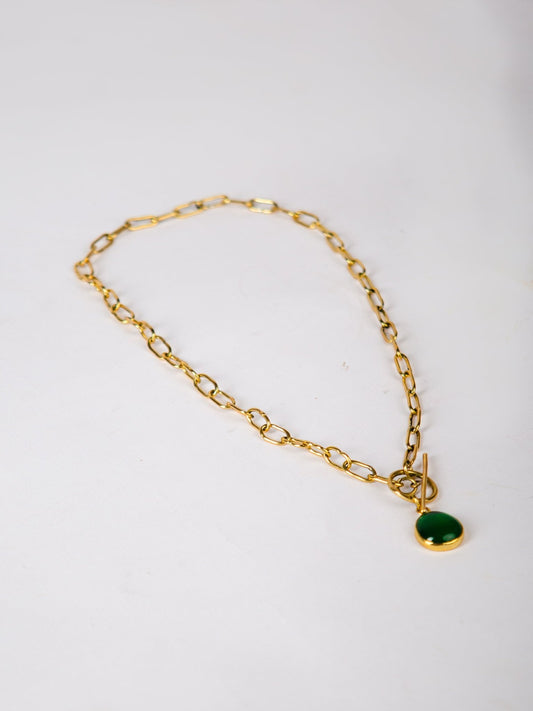 Gold chain bracelet with a green pendant on a white background