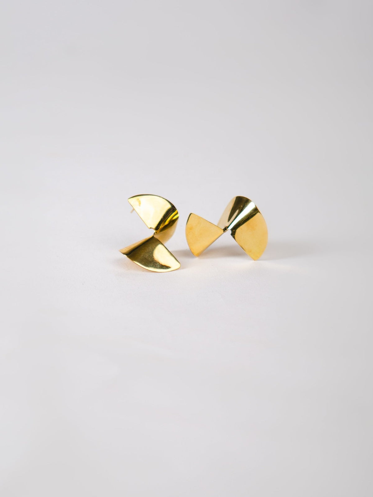 Pair of gold geometric earrings on a light gray background