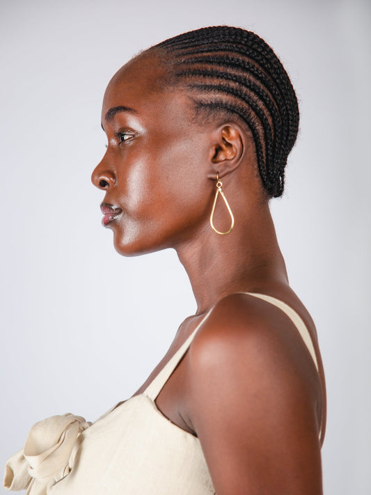 Woman with styled hair and gold earring on a plain background