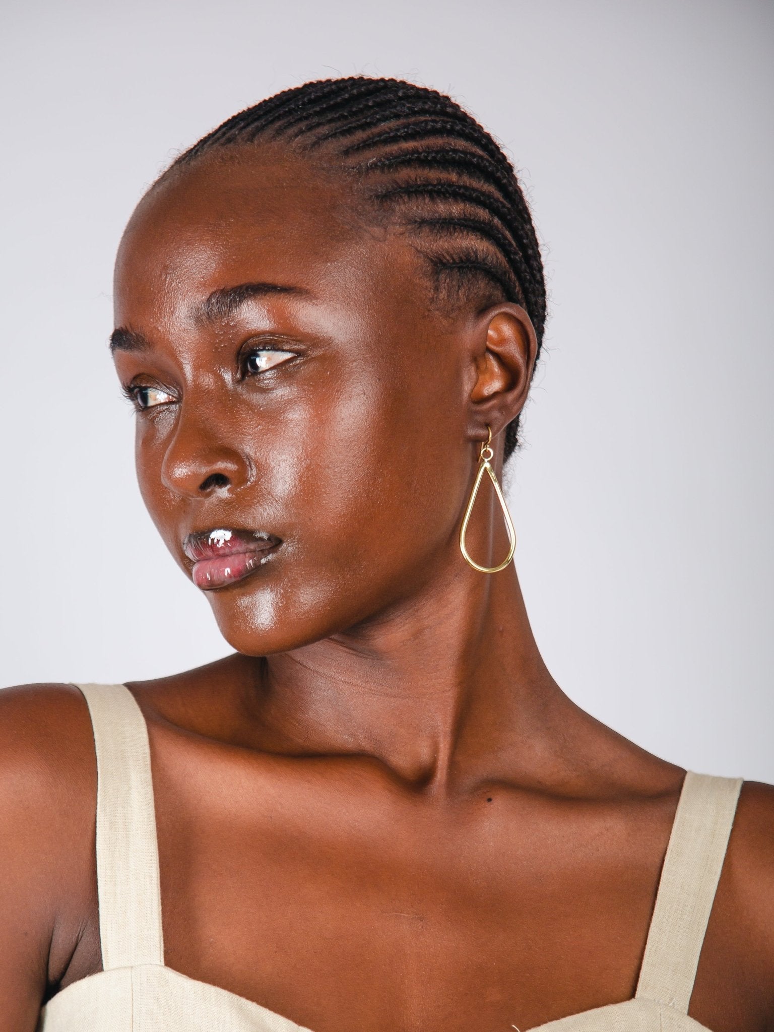 Woman with braided hair wearing a beige top against a white background