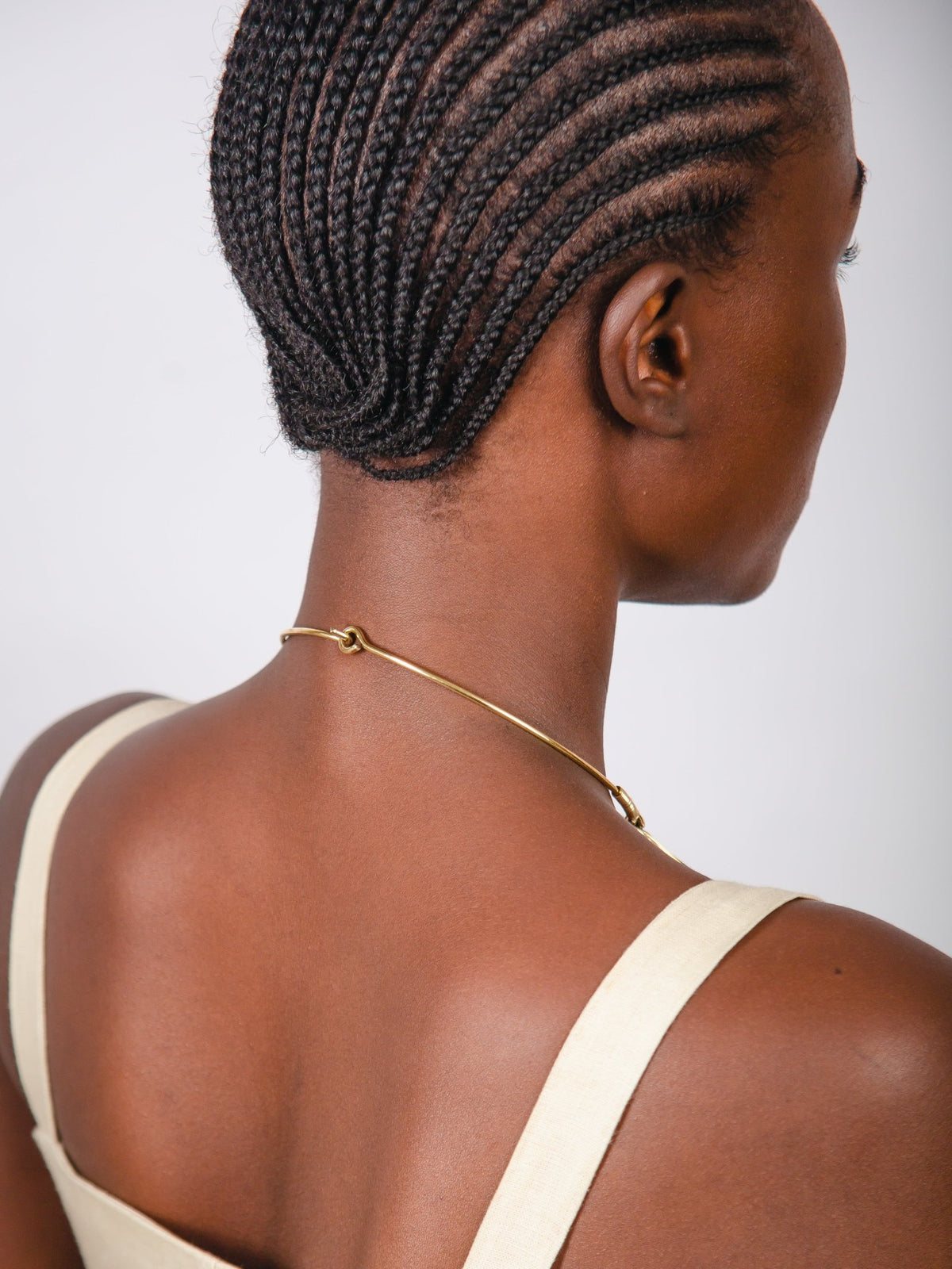 Woman with braided hair wearing a beige top against a white background