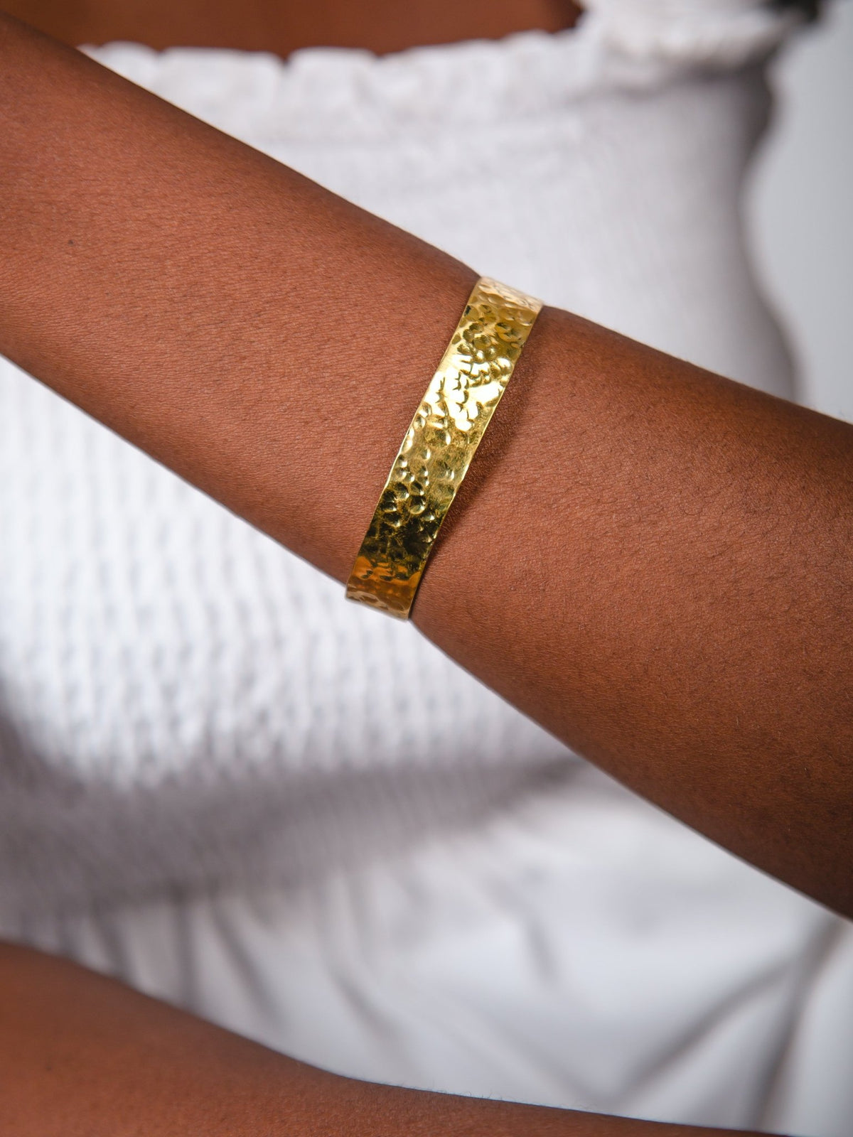 Gold bracelet on a person's wrist against a white background