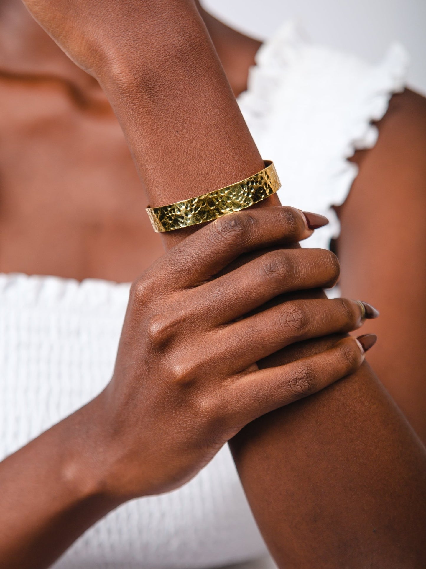 Close-up of a hand wearing a gold bracelet on a blurred background