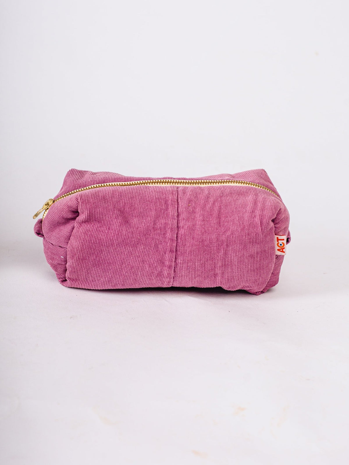 Pink corduroy pouch with a gold zipper on a white background