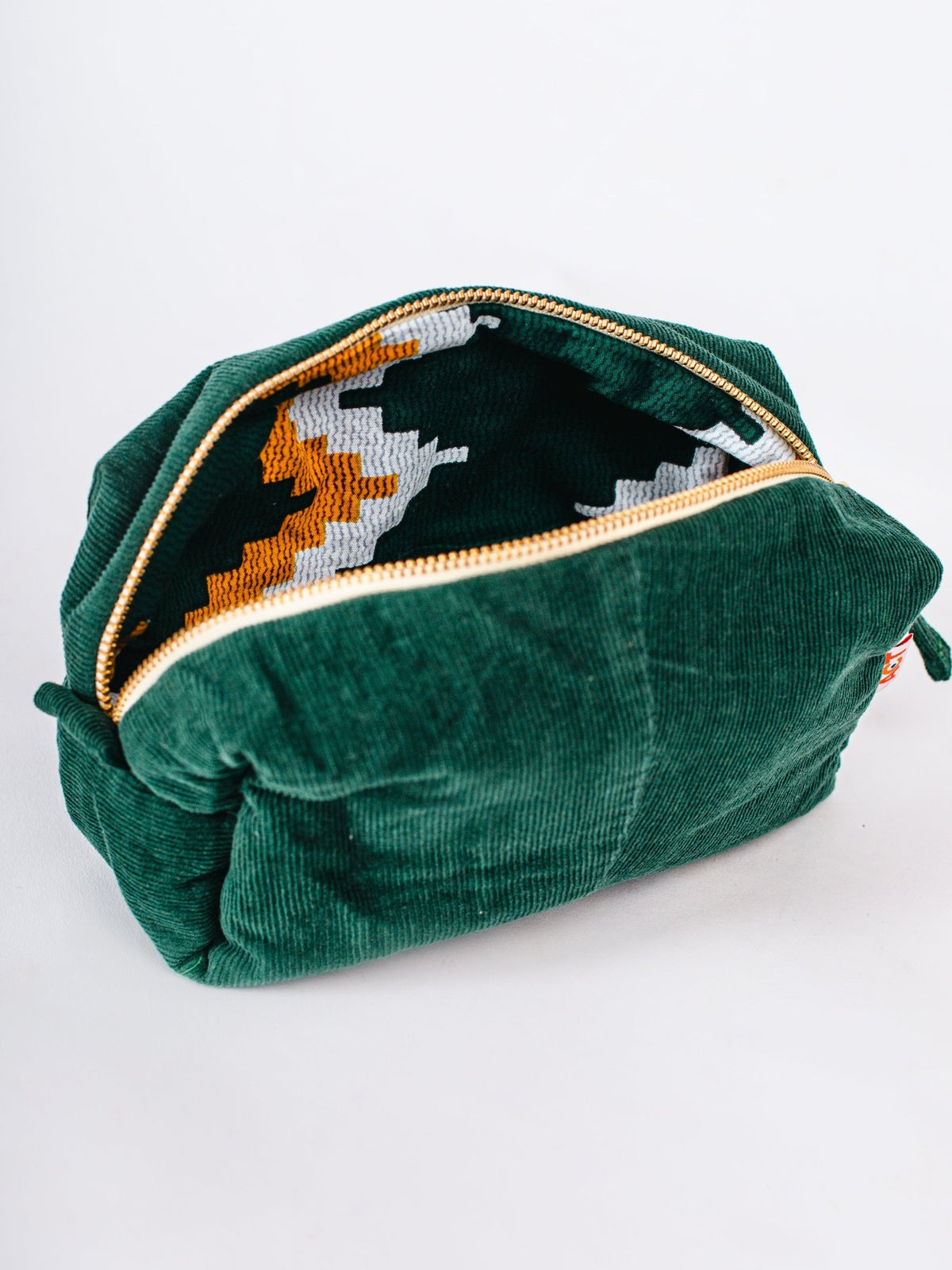 Green velvet pouch with a patterned interior on a white background