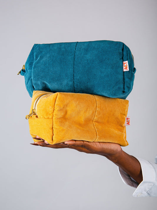 Hand holding a teal and yellow fabric against a gray background