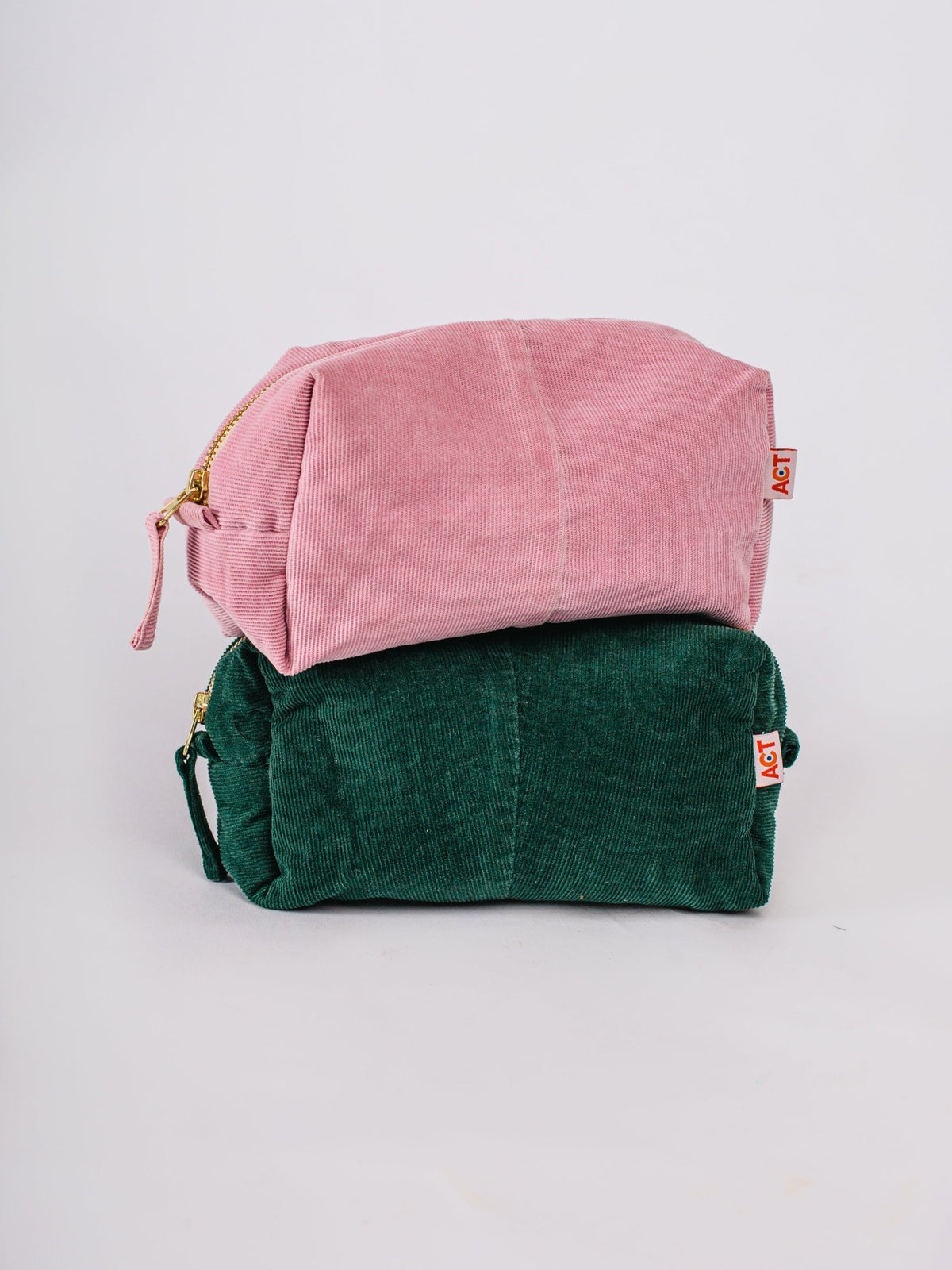 Pink and green fabric bags stacked on a light gray background