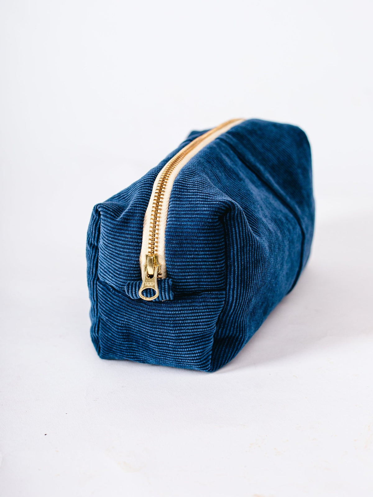 Blue velvet pouch with a gold zipper on a white background