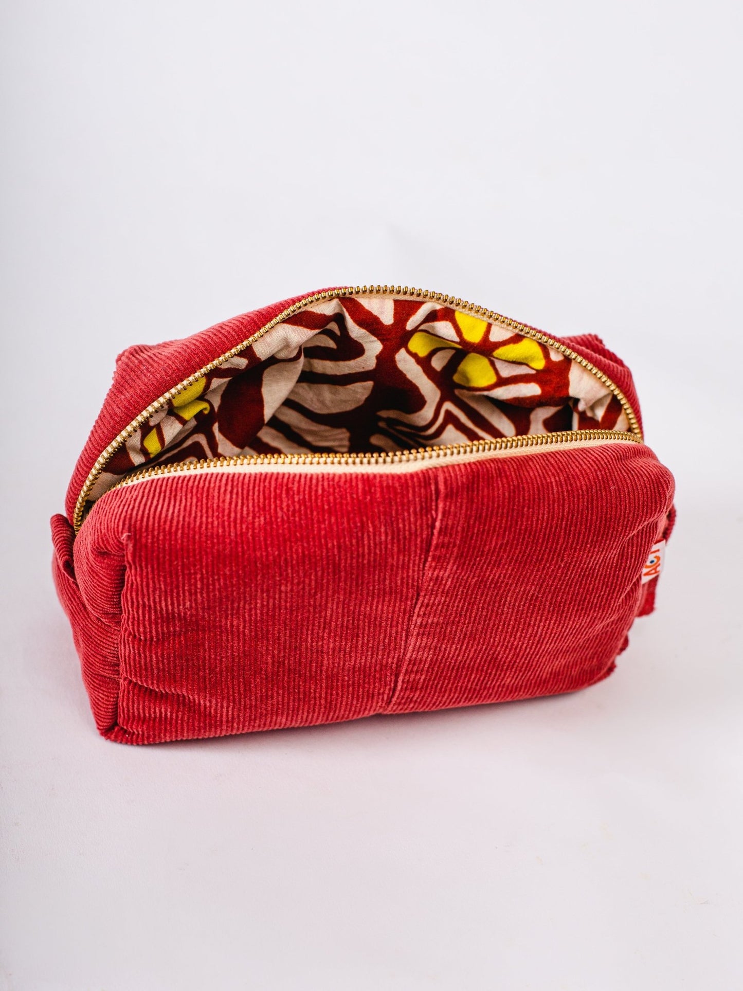 Red corduroy pouch with a colorful interior on a white background