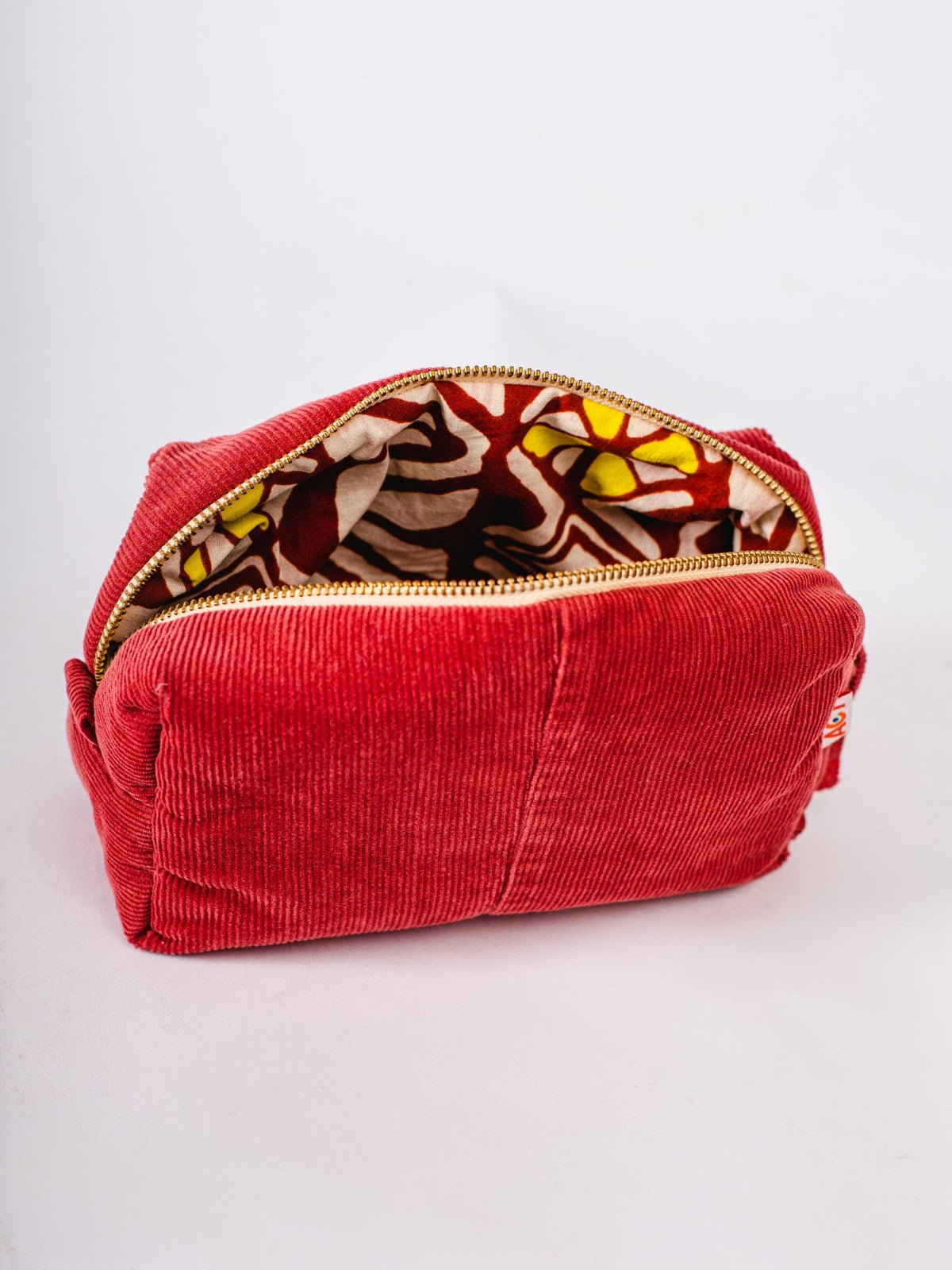Red corduroy pouch with a colorful interior on a white background