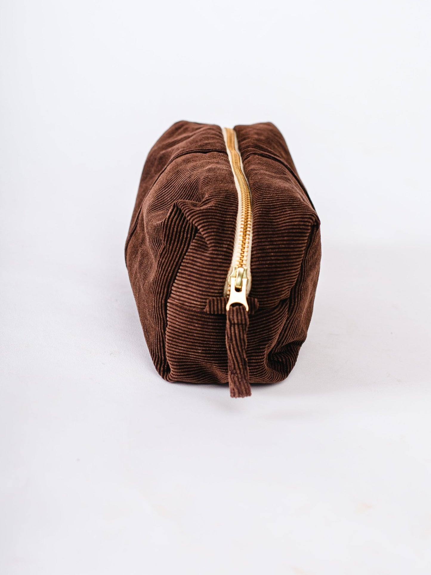 Brown corduroy pouch with a gold zipper on a white background
