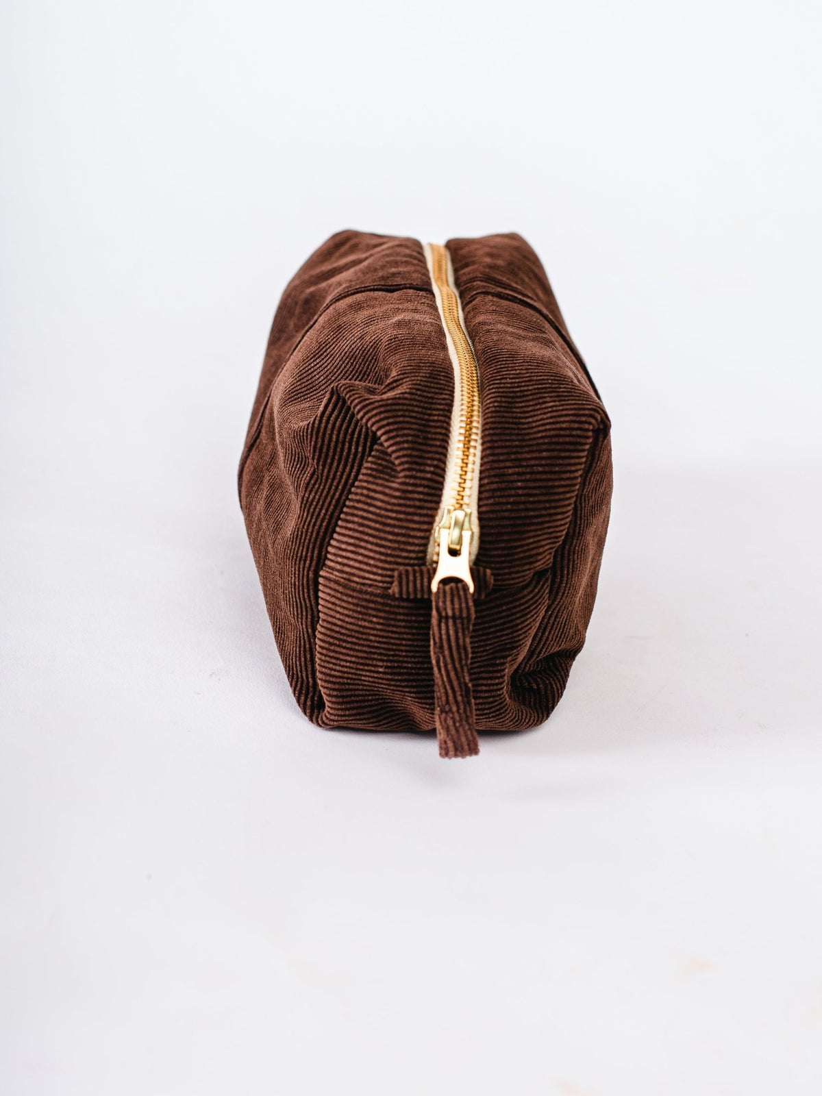 Brown corduroy pouch with a gold zipper on a white background
