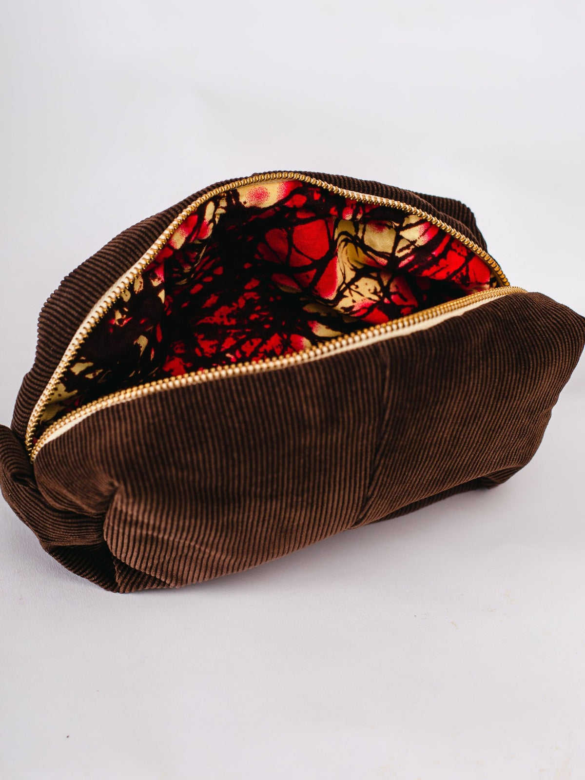 Brown corduroy pouch with a red and black patterned interior on a white background