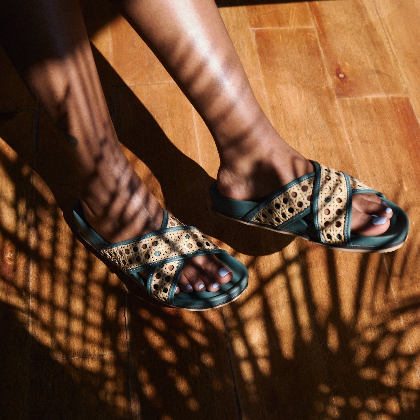 Close-up of feet wearing patterned sandals on a wooden floor