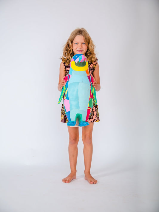 Child holding a colourful penguin  sculpture against a white background