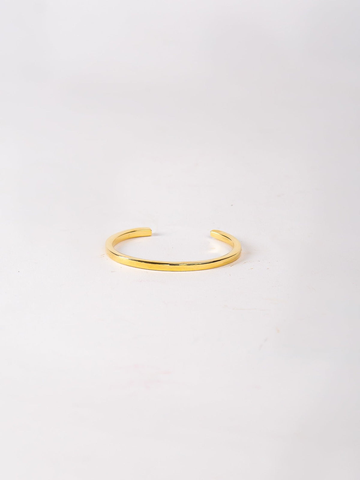 Gold bracelet on a light gray background