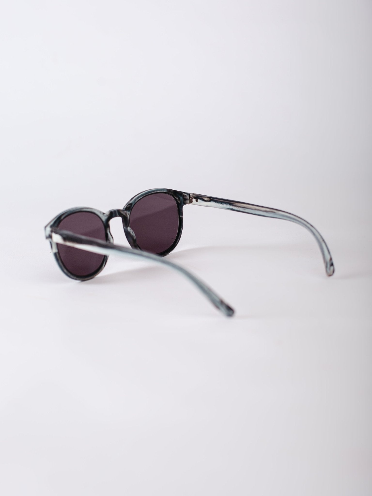 Sunglasses with dark lenses and thin metal frame on a light gray background