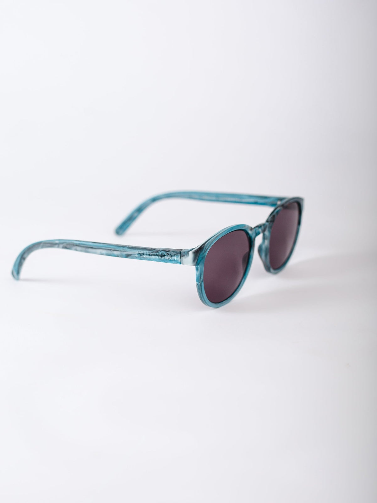 Teal sunglasses with dark lenses on a white background