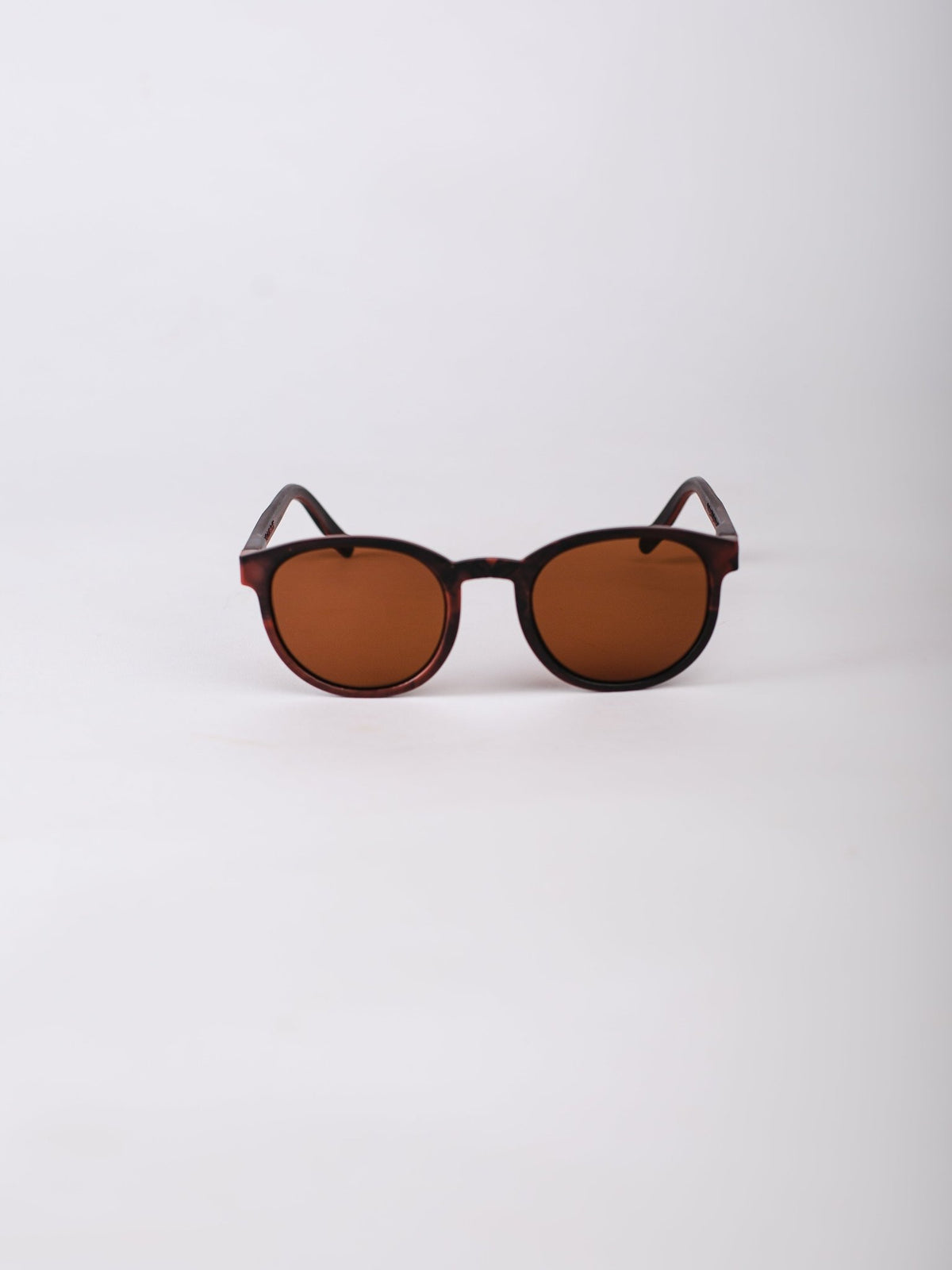 Round sunglasses with brown lenses and black frames on a white background