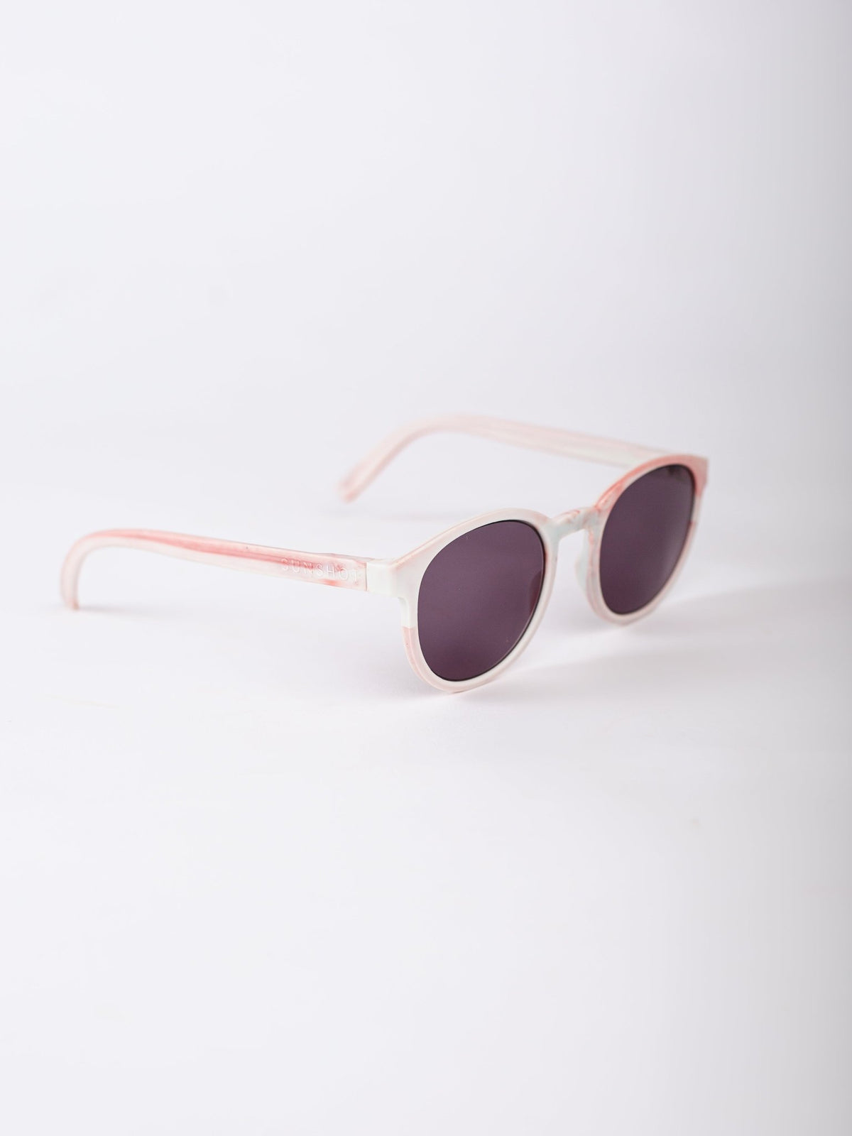 Sunglasses with pink frame and dark lenses on a white background