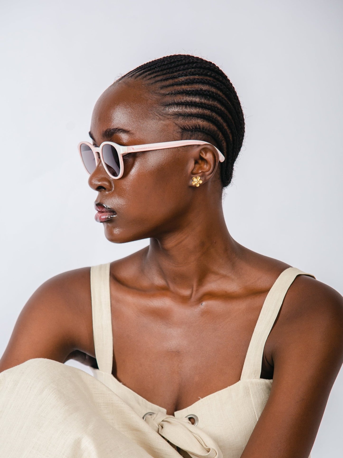Woman wearing sunglasses and a beige dress against a white background