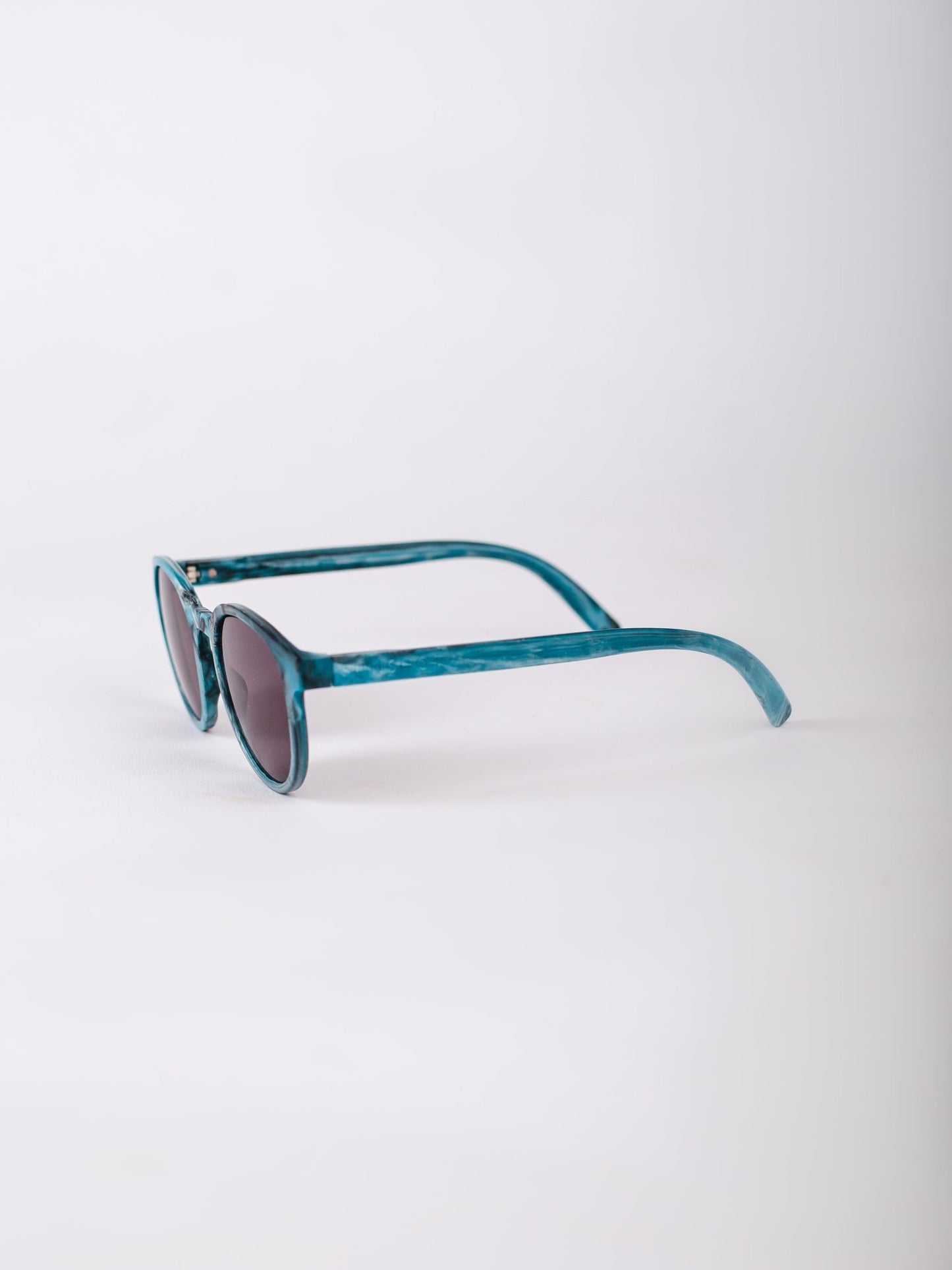 Teal sunglasses on a light gray background