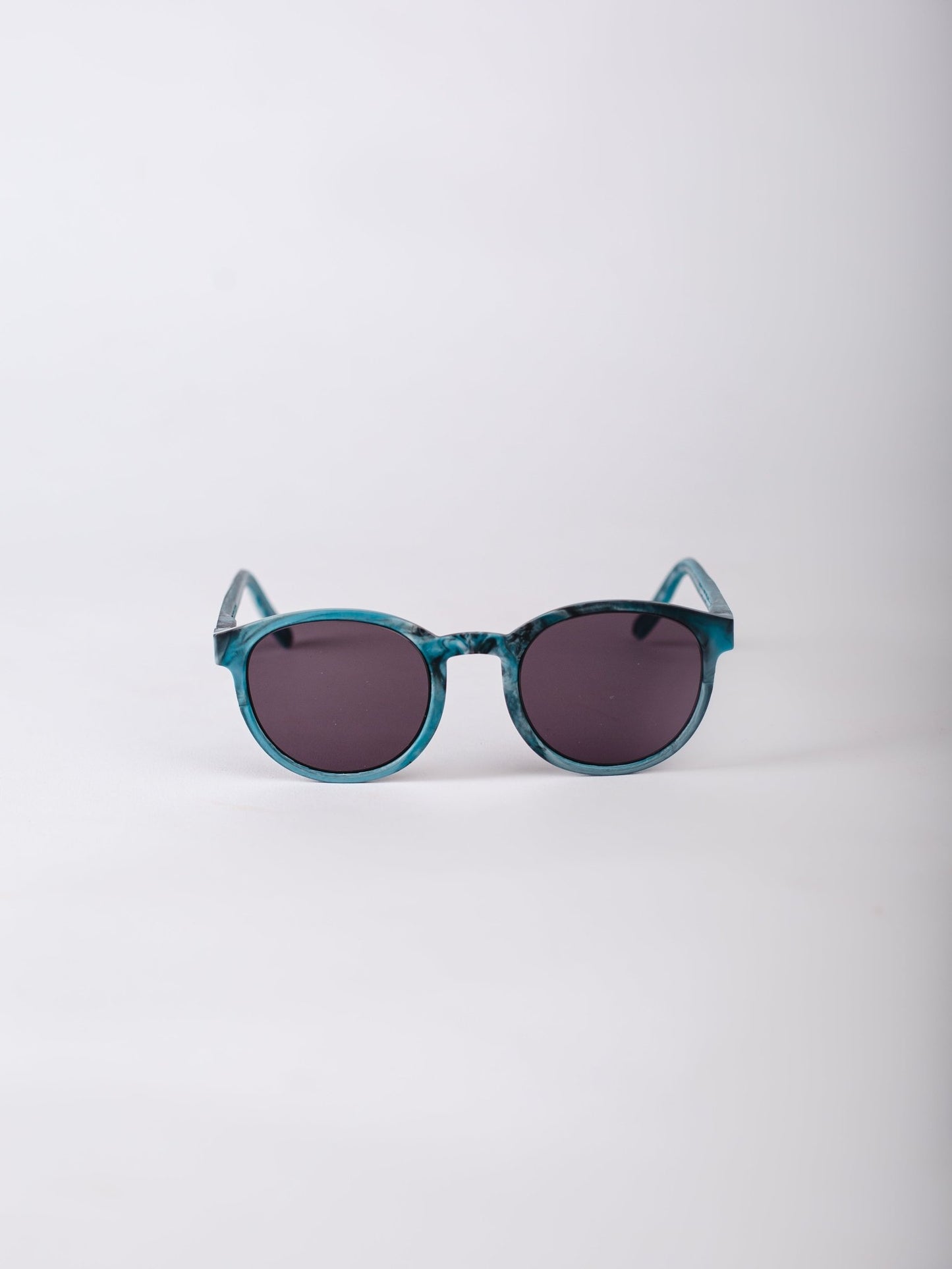 Teal sunglasses with dark lenses on a light gray background