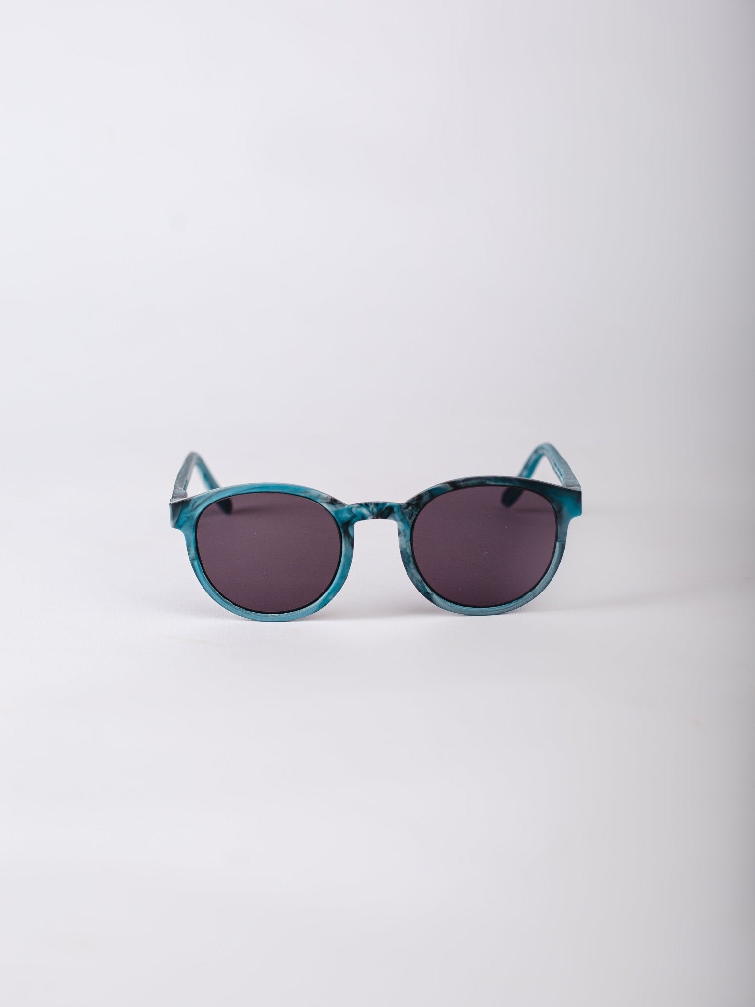 Teal sunglasses with dark lenses on a light gray background