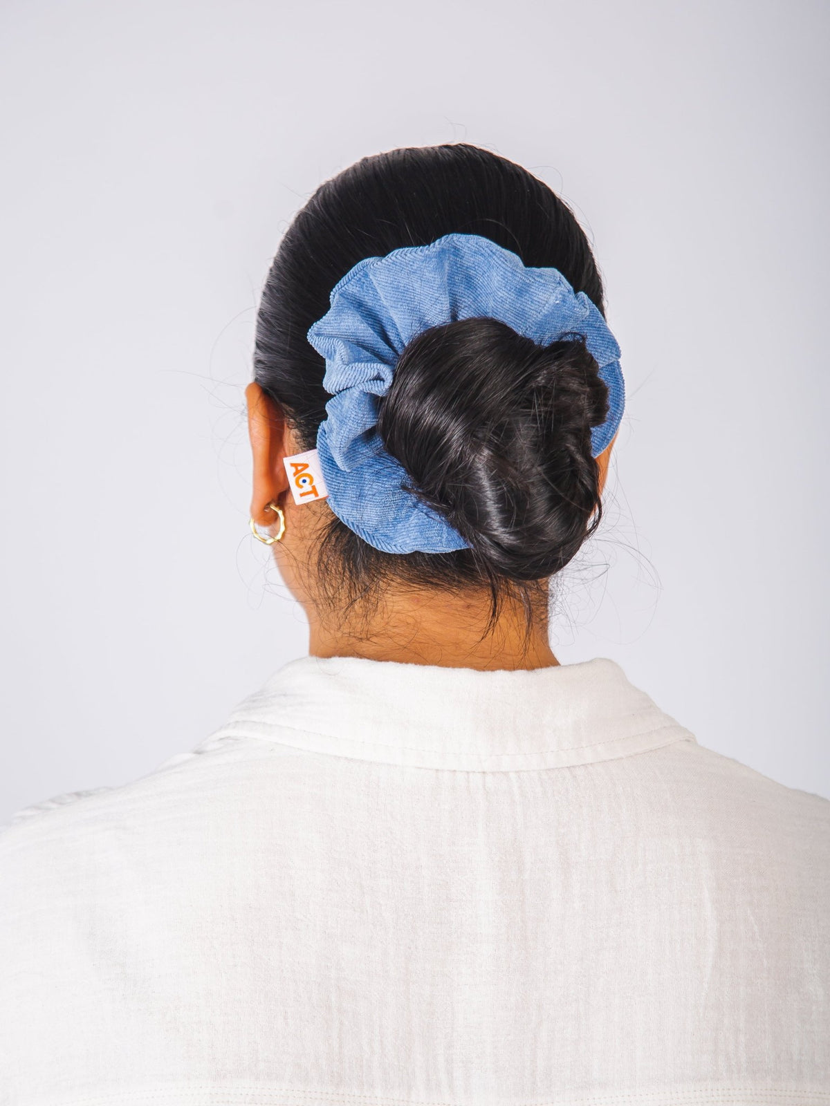 Person with a blue scrunchie in their hair against a white background